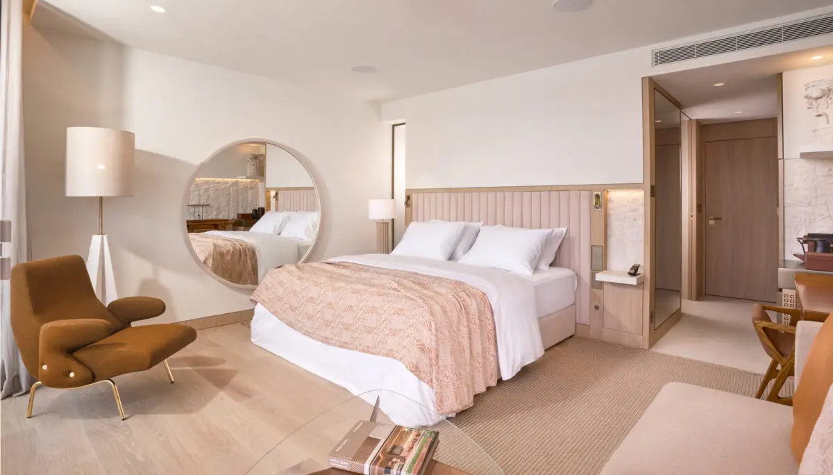 Villa Dubrovnik hotel room with a large round mirror, bed, and modern chair. Croatia destination wedding hotel.