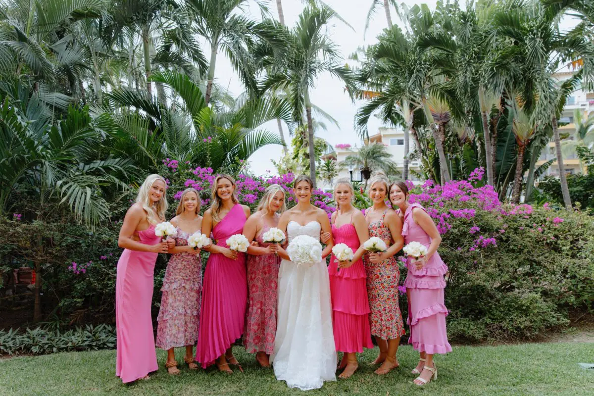 Bride and bridesmaids at a Puerto Vallarta wedding, posing in front of tropical foliage