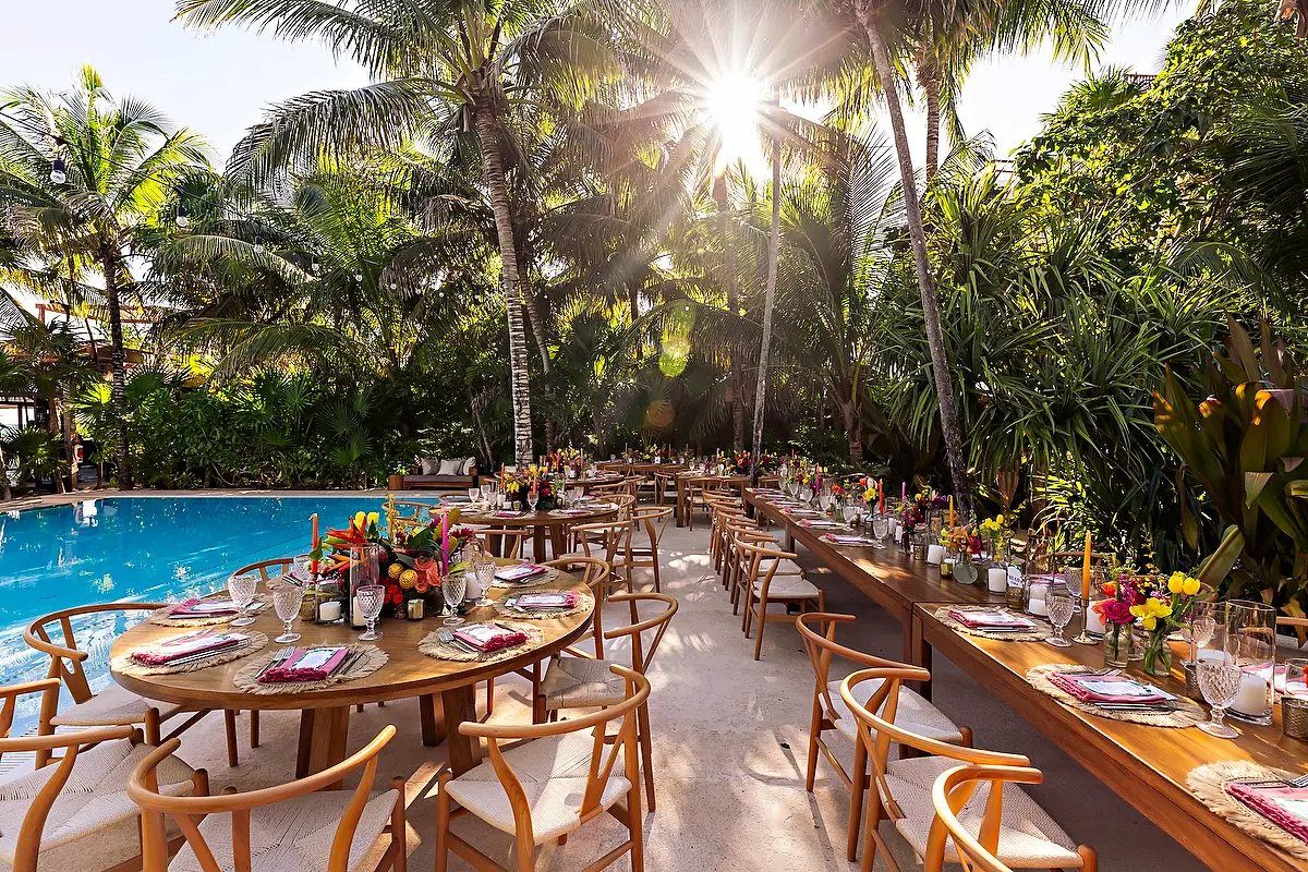 Jashita Hotel Tulum wedding venue with poolside reception tables under palm trees in bright sunlight.