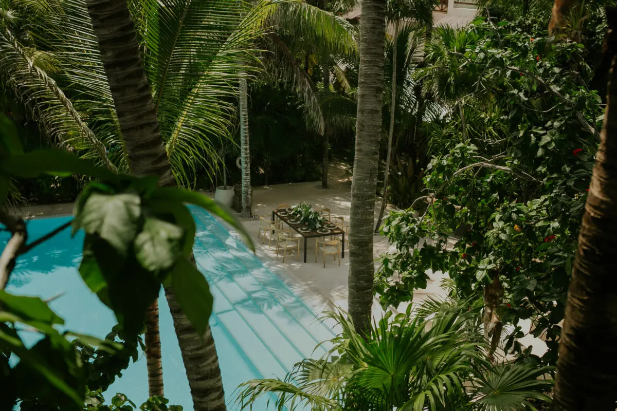 Jashita Hotel Tulum wedding venue poolside dining table setting, surrounded by palm trees.