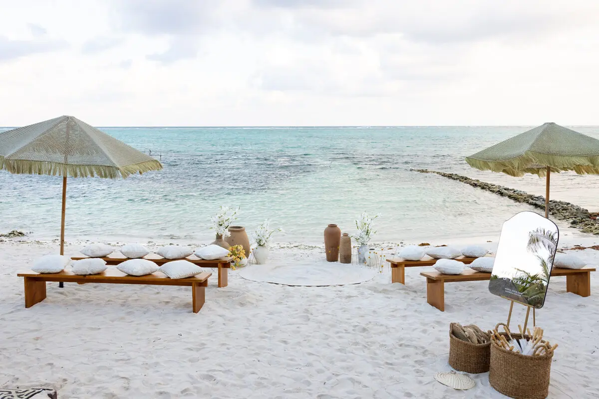 Beach wedding setup at Jashita Hotel Tulum, with benches, umbrellas, and ocean view. Tulum Wedding Venue.