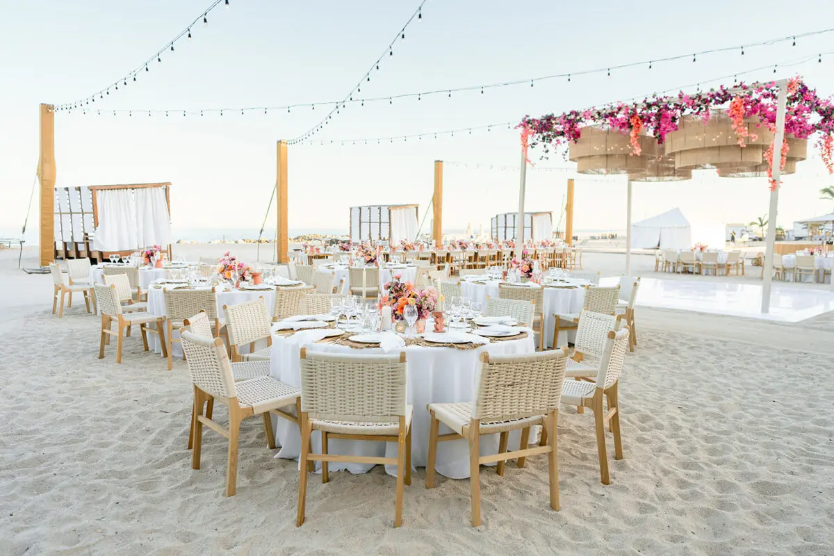 Los Cabos destination wedding reception on the beach with round tables and string lights.