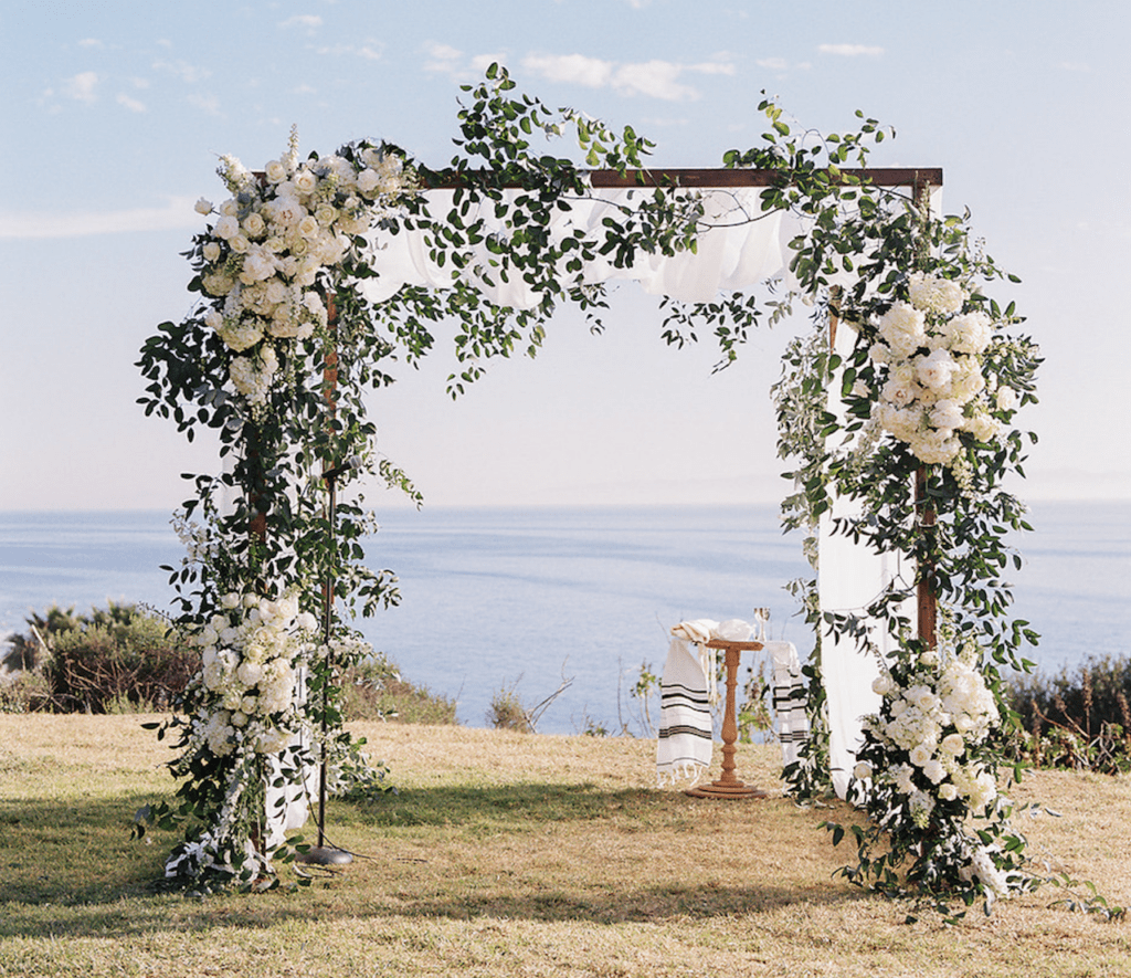 Floral Jewish wedding chuppah overlooking the ocean
