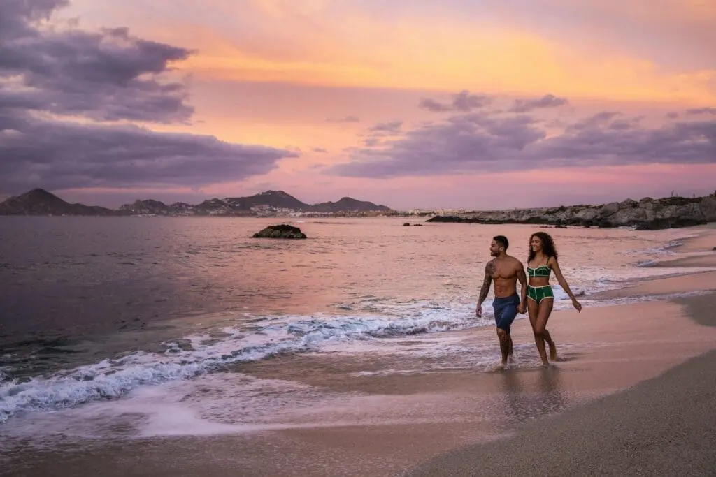 Couple walking on a beach at sunset, perfect for a romantic elopement