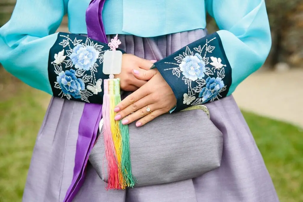Woman in traditional Korean hanbok with floral embroidery and colorful tassel