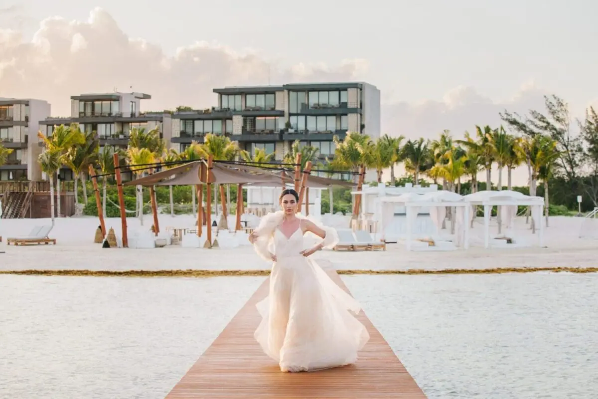 Bride in flowing wedding gown on a resort dock in Mexico.