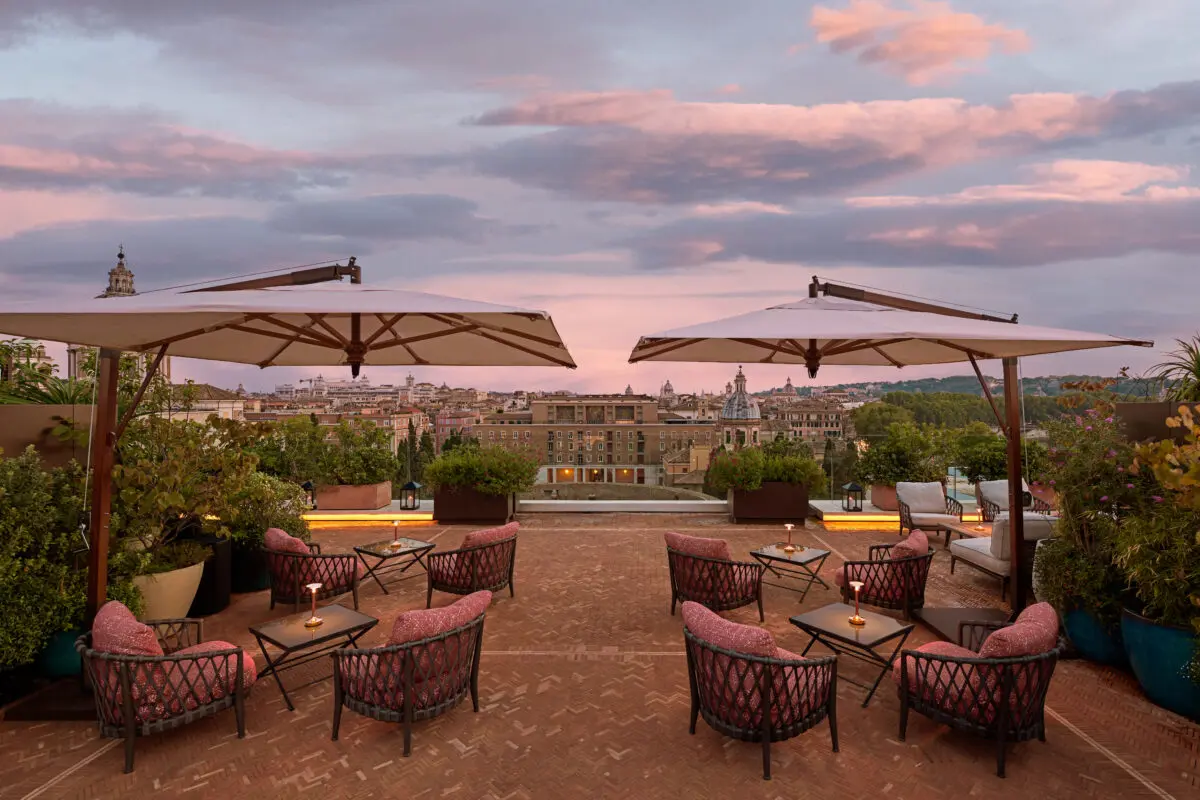 Rooftop lounge with city views, chairs, and umbrellas at dusk. Property descriptions meaning.