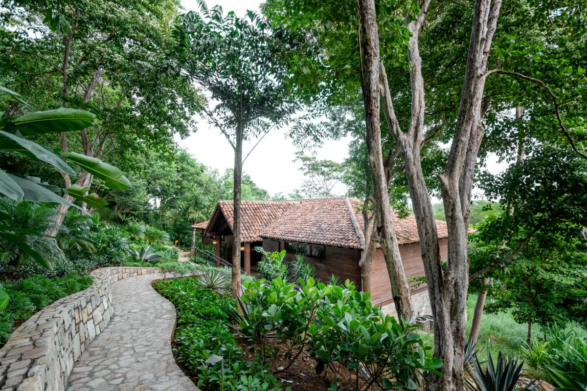 Stone path leading to a rustic building amidst lush greenery at Rancho Santana