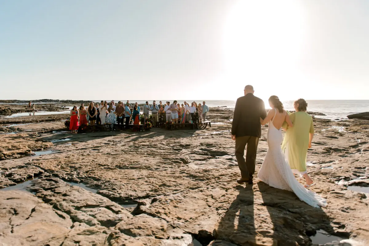 Rancho Santana wedding on a rocky beach with guests watching.