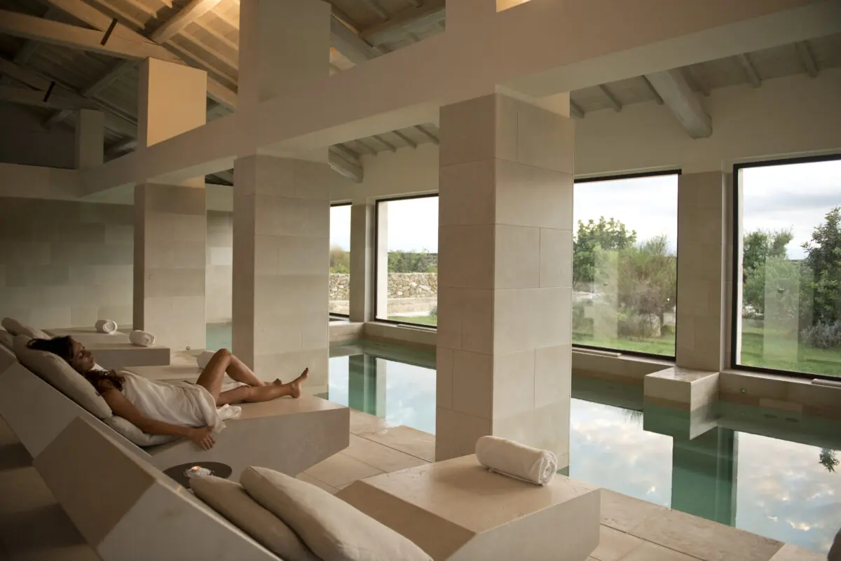 Woman relaxing by the indoor pool at Relais Histò Hotel & SPA. Luxury spa retreat.