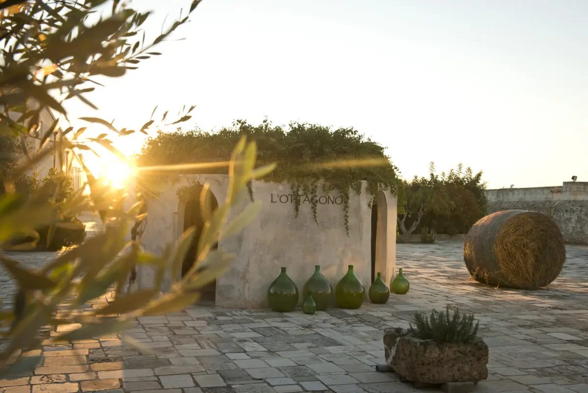 L'Ottagono building with green bottles and hay bale at Relais Histò Hotel & SPA.