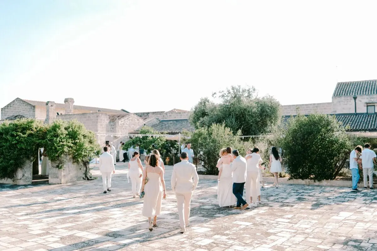 Wedding guests at Relais Histò Hotel & SPA courtyard in white attire.