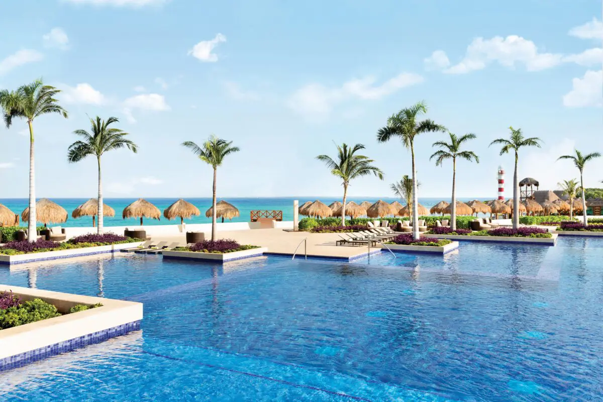 Hyatt Ziva Cancun pool view with palm trees and beach umbrellas.