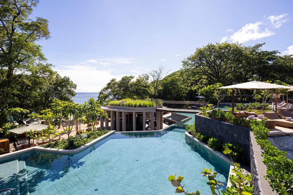 Waldorf Astoria Costa Rica: Luxurious pool area with ocean views, lush greenery, and modern architecture.