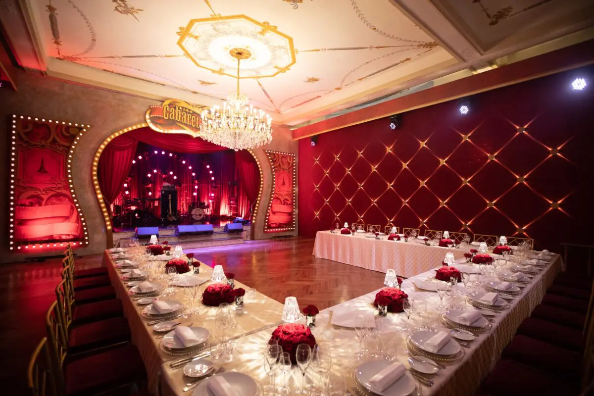 Elegant wedding reception at COMO Le Beauvallon, Saint-Tropez. Luxurious table setting with red roses, stage in background.