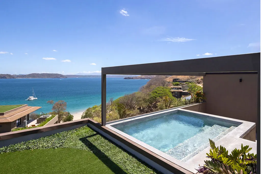 Waldorf Astoria Costa Rica: Rooftop pool with ocean view, boat, and lush greenery.