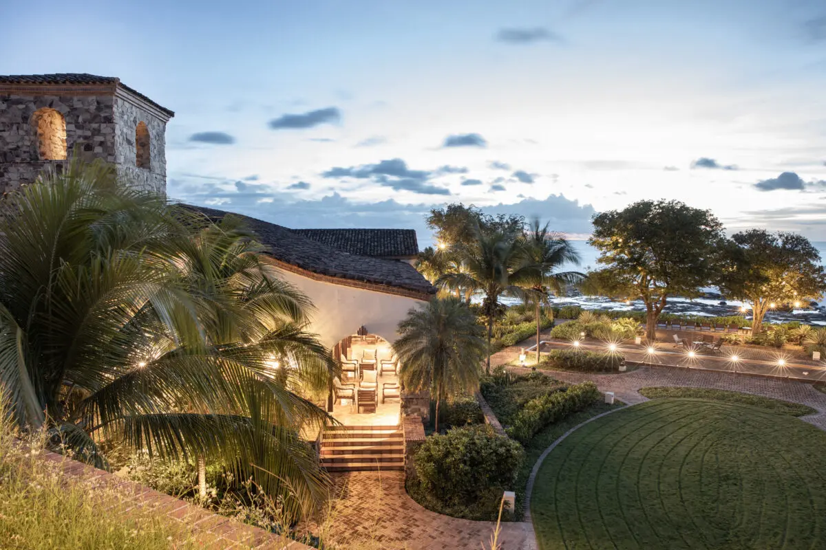 Rancho Santana resort at dusk, featuring architecture, palm trees, and ocean view.