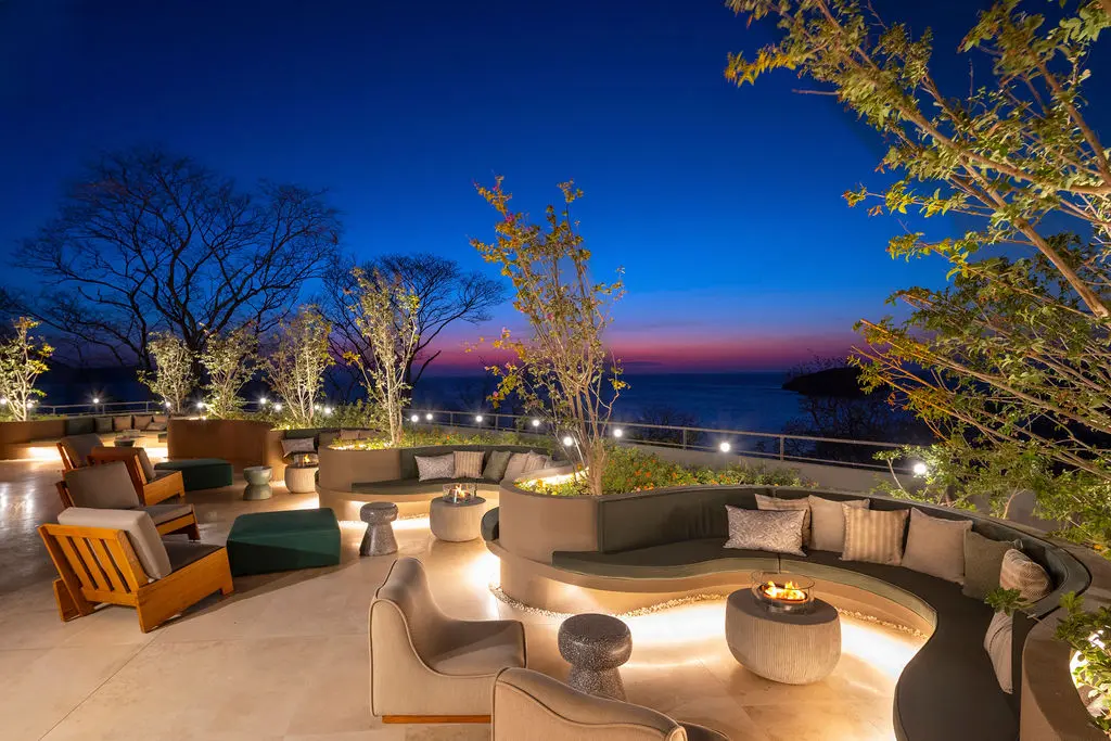 Waldorf Astoria Costa Rica outdoor lounge area at dusk with seating, tables, and ocean view.