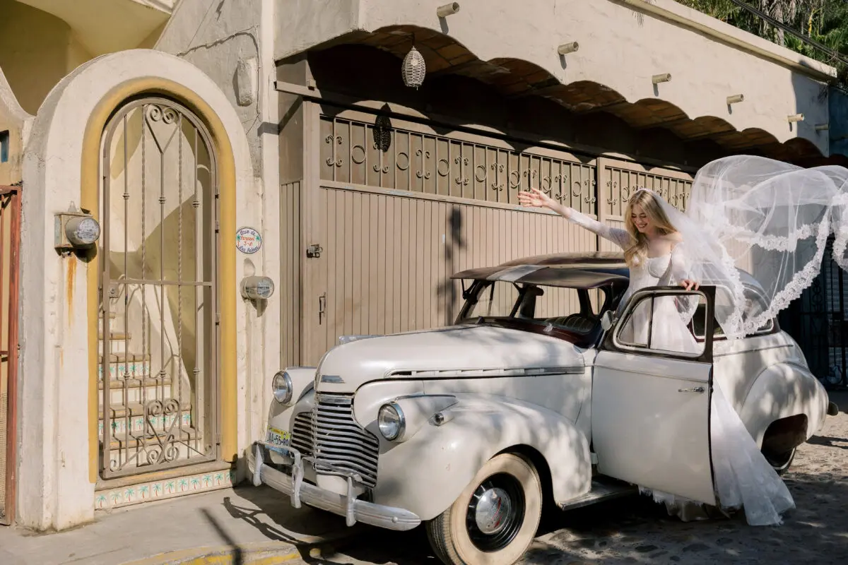 Bride exiting a vintage car in a destination wedding resort, showcasing what couples expect for luxury weddings.