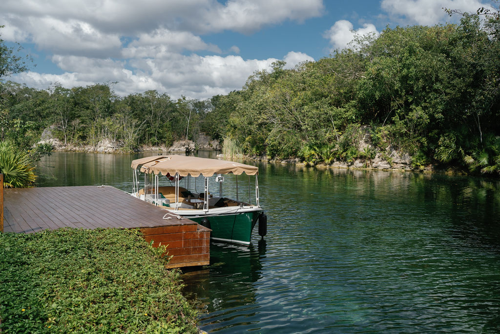 Boat docked at Banyan Tree Mayakoba, ready for Riviera Maya ceremonies. Lush greenery surrounds the tranquil water.