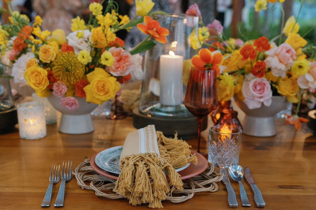 Riviera Maya Ceremonies table setting with vibrant floral arrangements and candles.