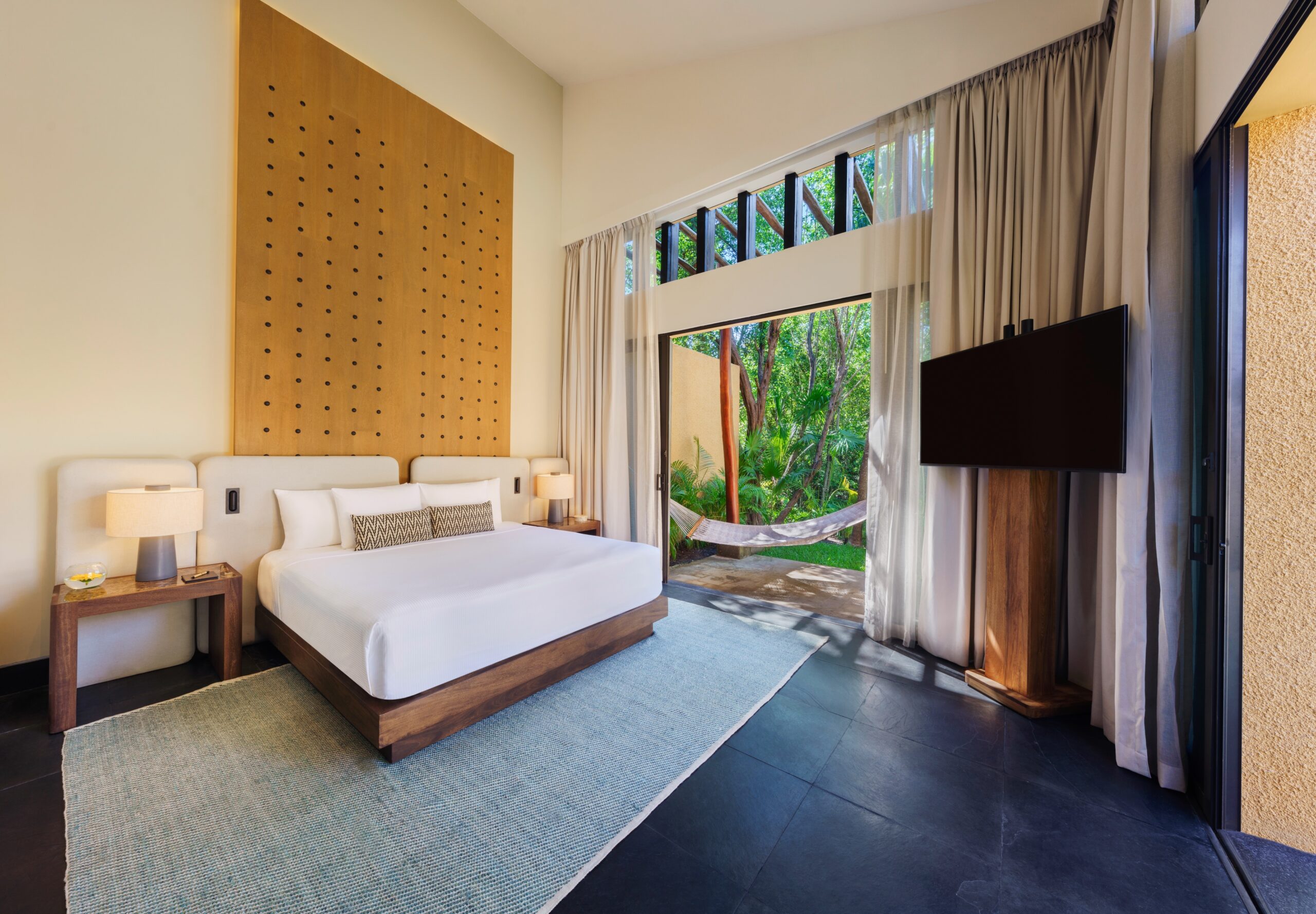 Luxury Banyan Tree Mayakoba suite featuring a king bed, patio, and tropical view. Riviera Maya Ceremonies could be held here.
