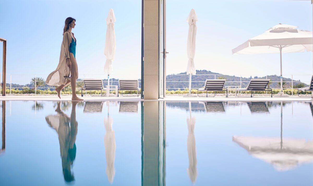 Woman walks barefoot by the pool at Villa Dubrovnik, a Croatia destination wedding hotel.