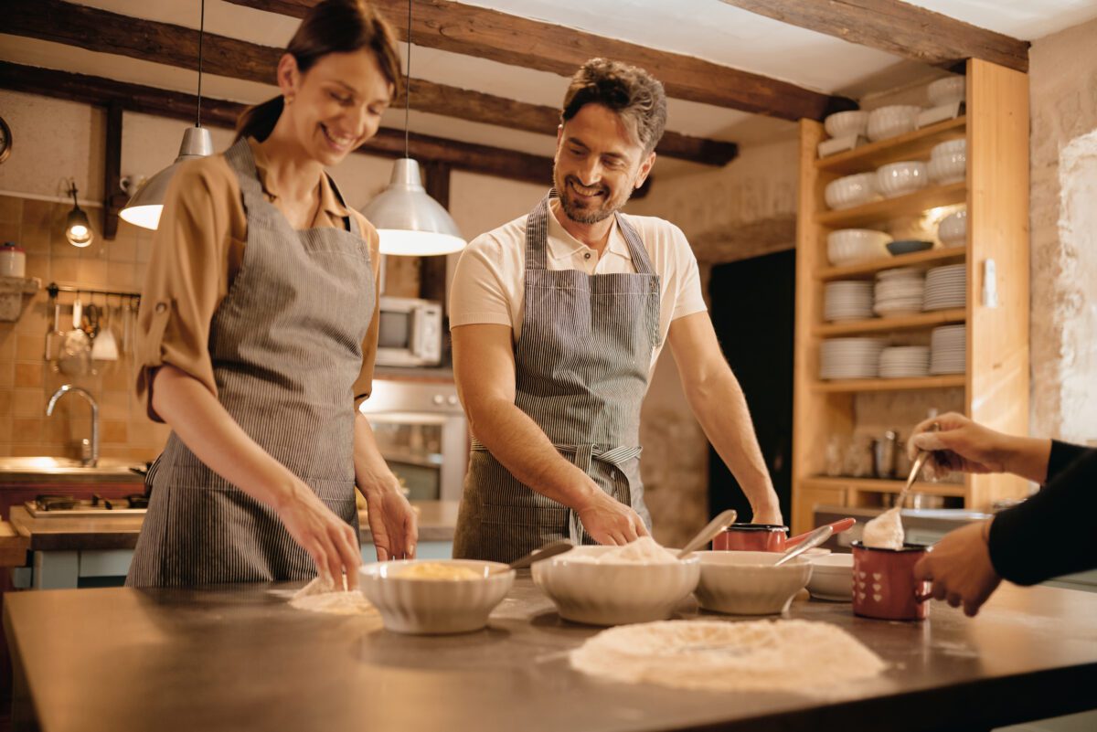Couple in aprons preparing food in a rustic kitchen