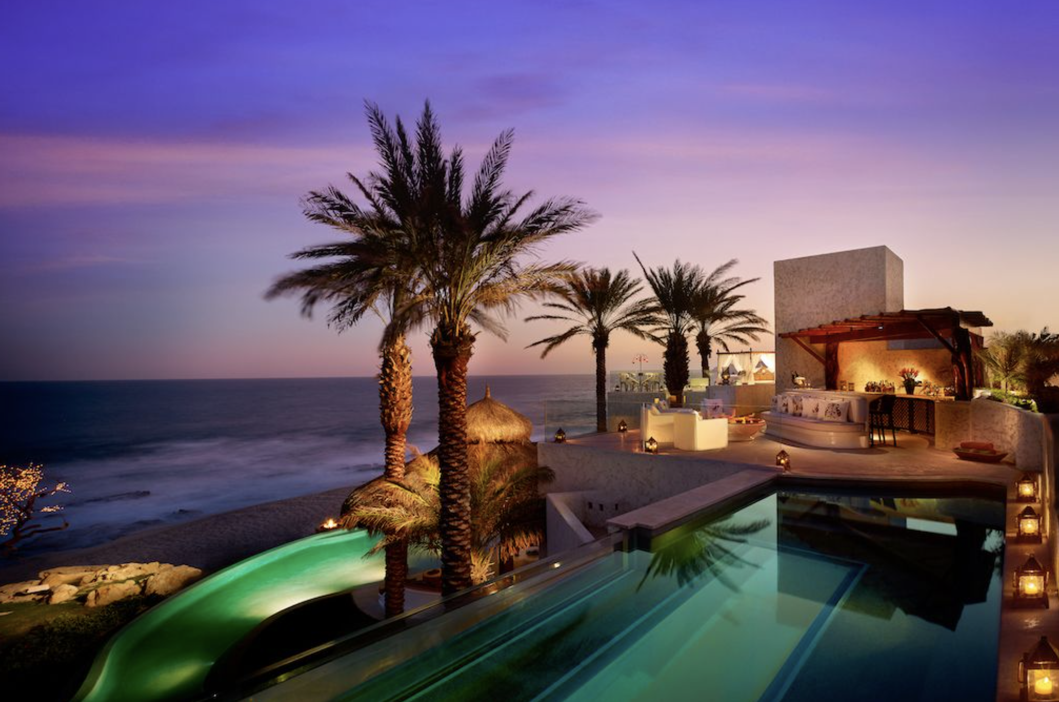 Luxury resort wedding location with pool, palm trees, and ocean view at sunset.