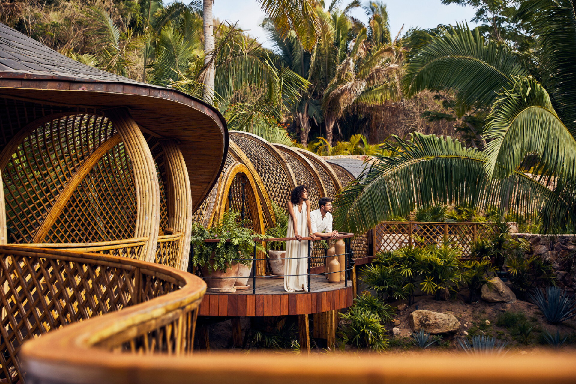 Couple on a tropical balcony, ideal wedding location with bamboo architecture and lush greenery.