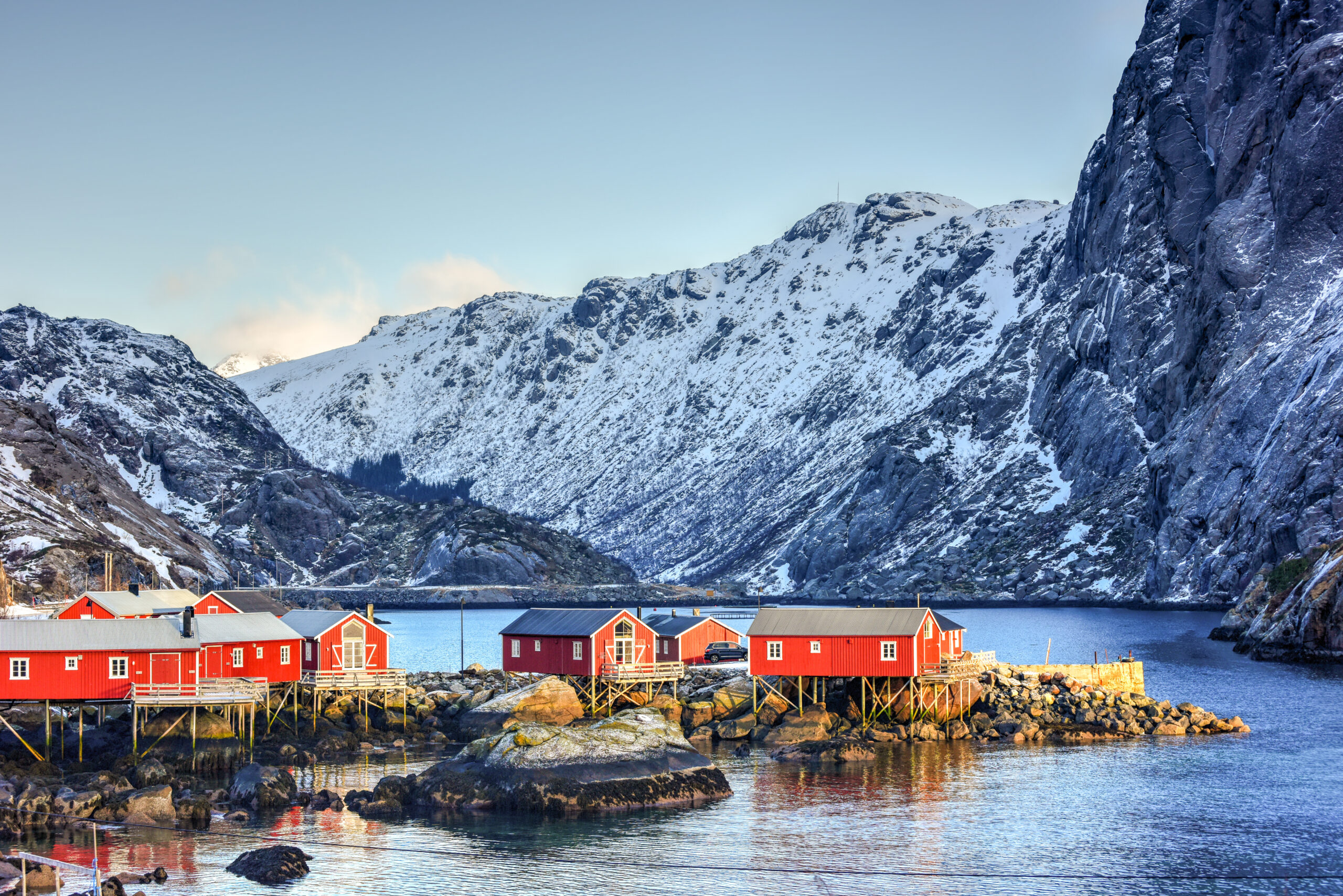 Red cabins on stilts in Lofoten, Norway, with snow-covered mountains. Dream wedding location inspiration.