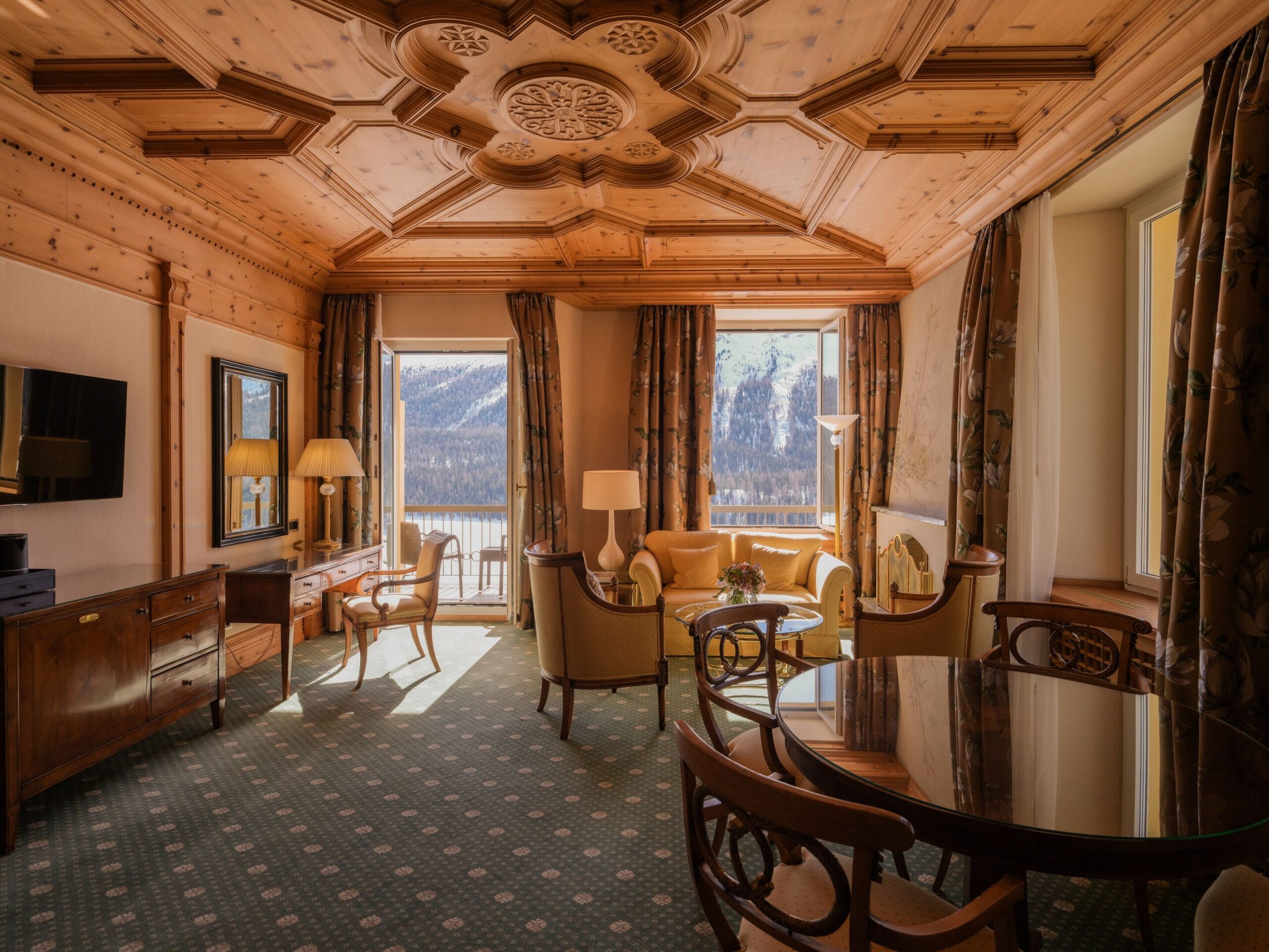 Luxurious suite at Kulm Hotel St. Moritz with wooden ceiling, elegant furniture, and mountain views. Perfect for a Switzerland wedding.