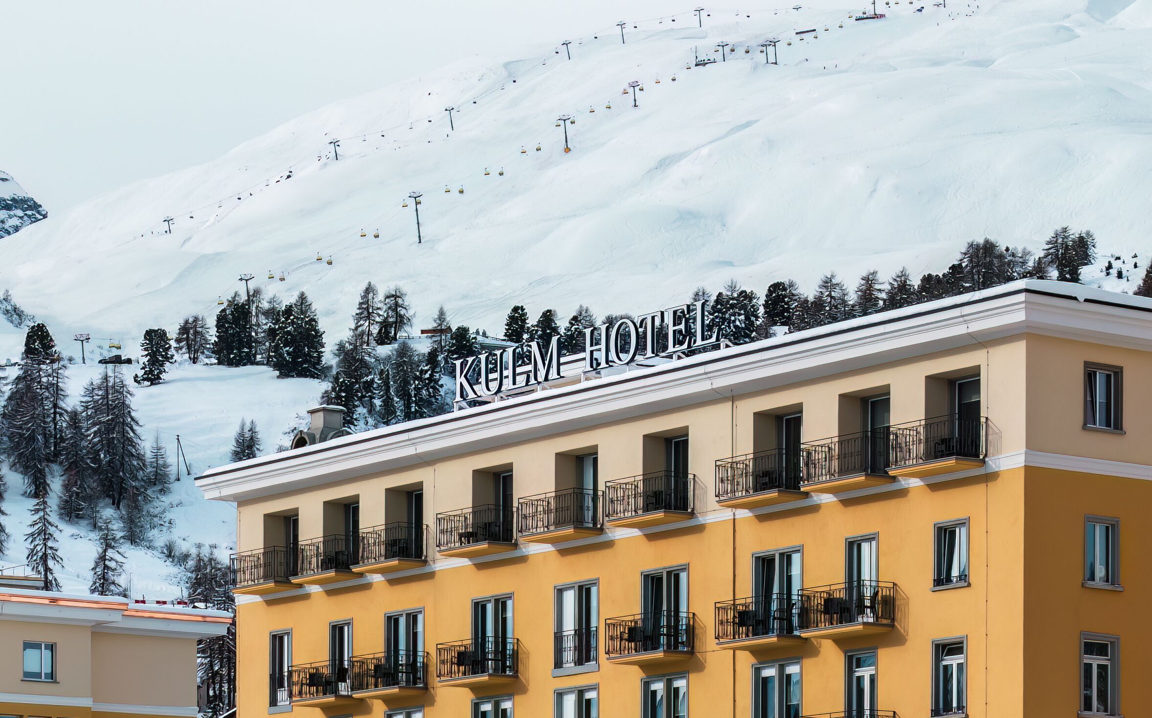 Kulm Hotel St. Moritz with ski slopes in the background.