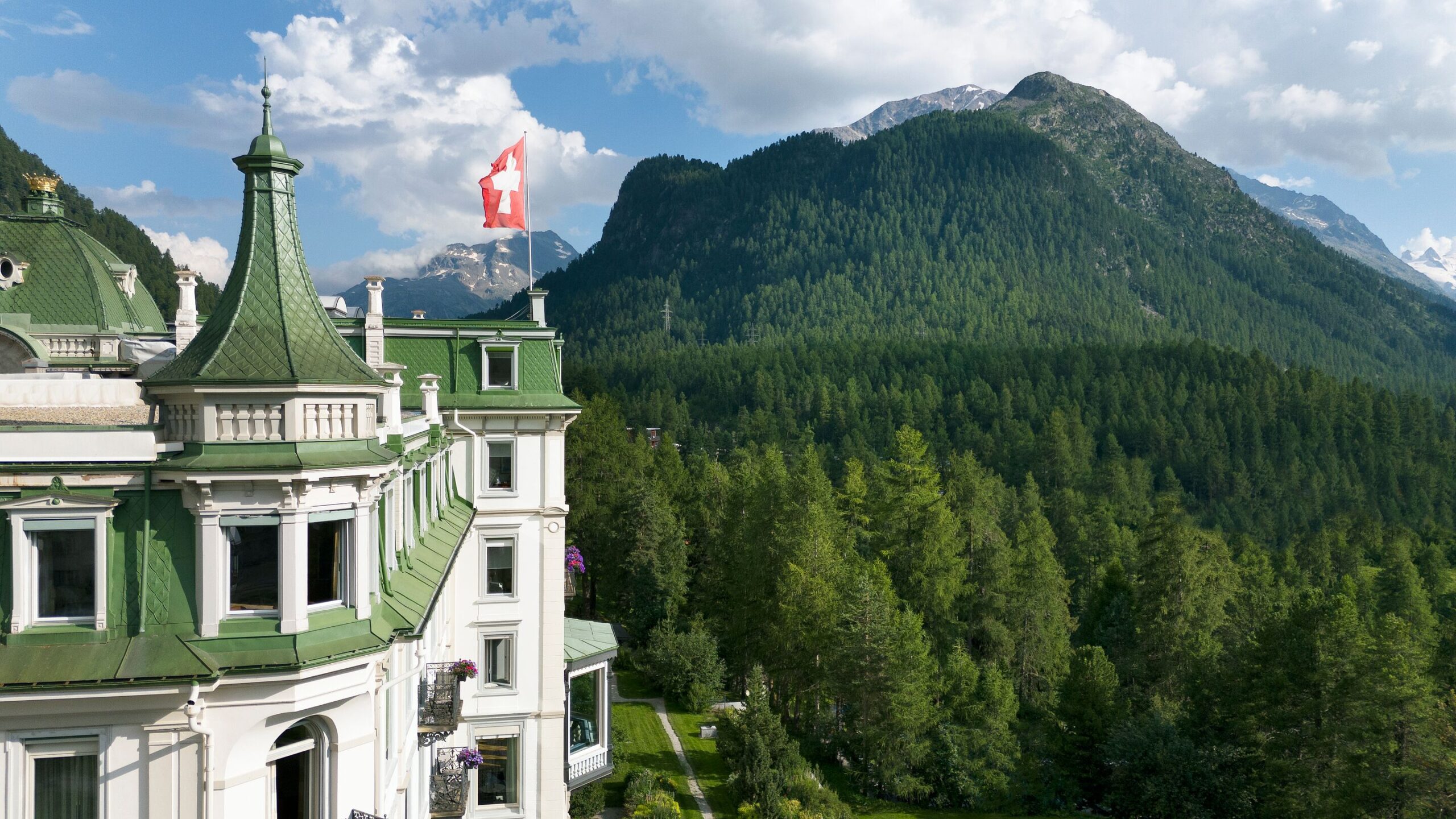 Grand Hotel Kronenhof with Swiss flag against the backdrop of the Swiss Alps.