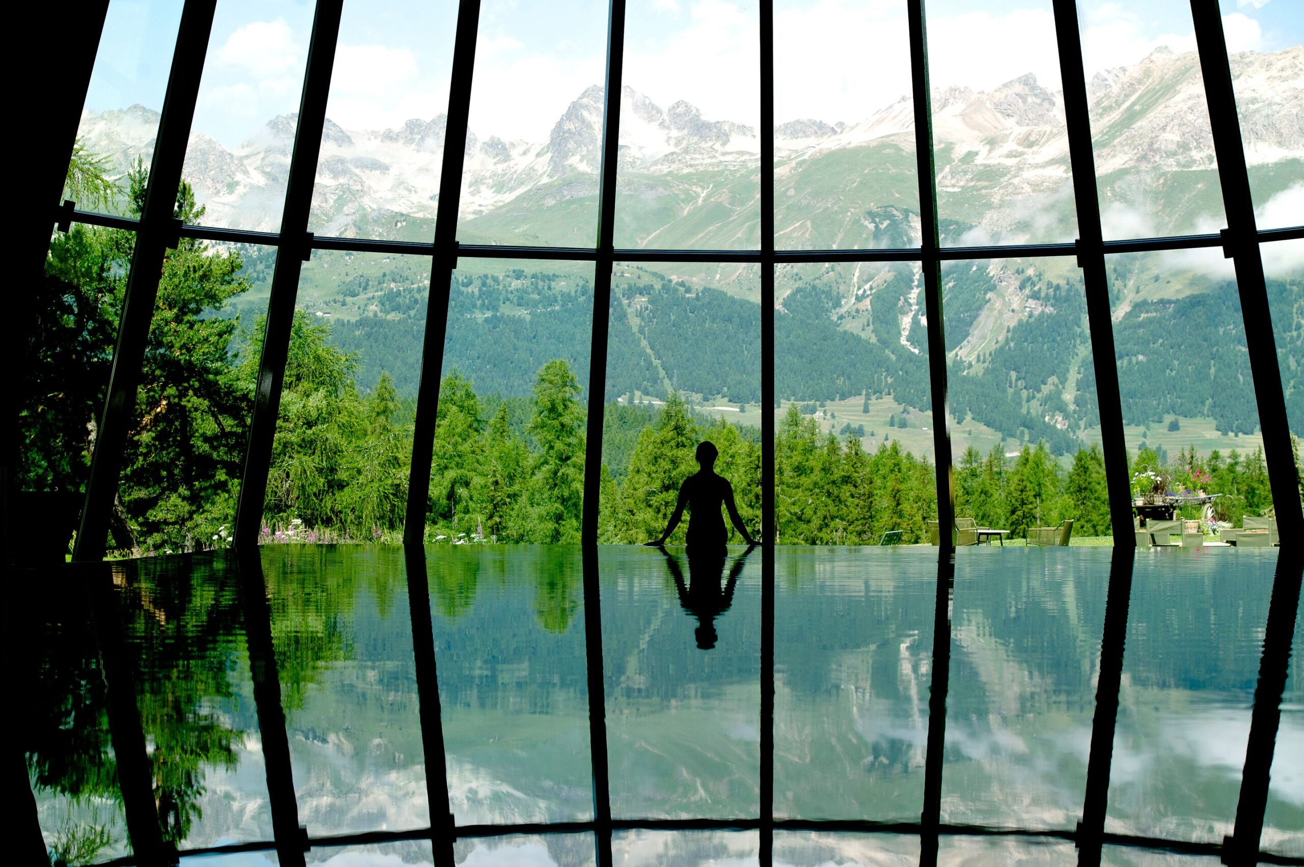 Silhouette in infinity pool at Grand Hotel Kronenhof, overlooking the Swiss Alps.