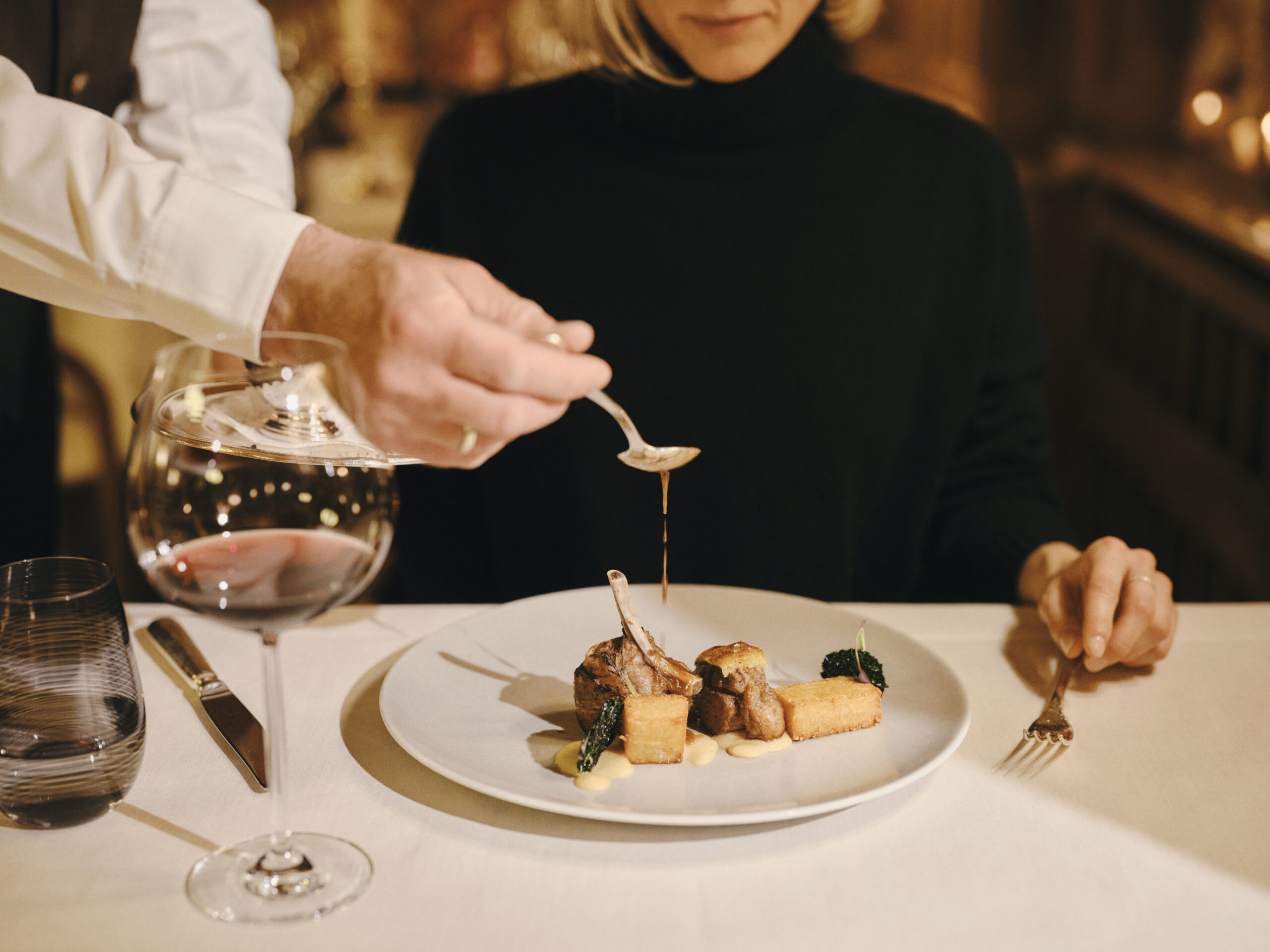 Fine dining at Grand Hotel Kronenhof: a chef serves a gourmet lamb dish.
