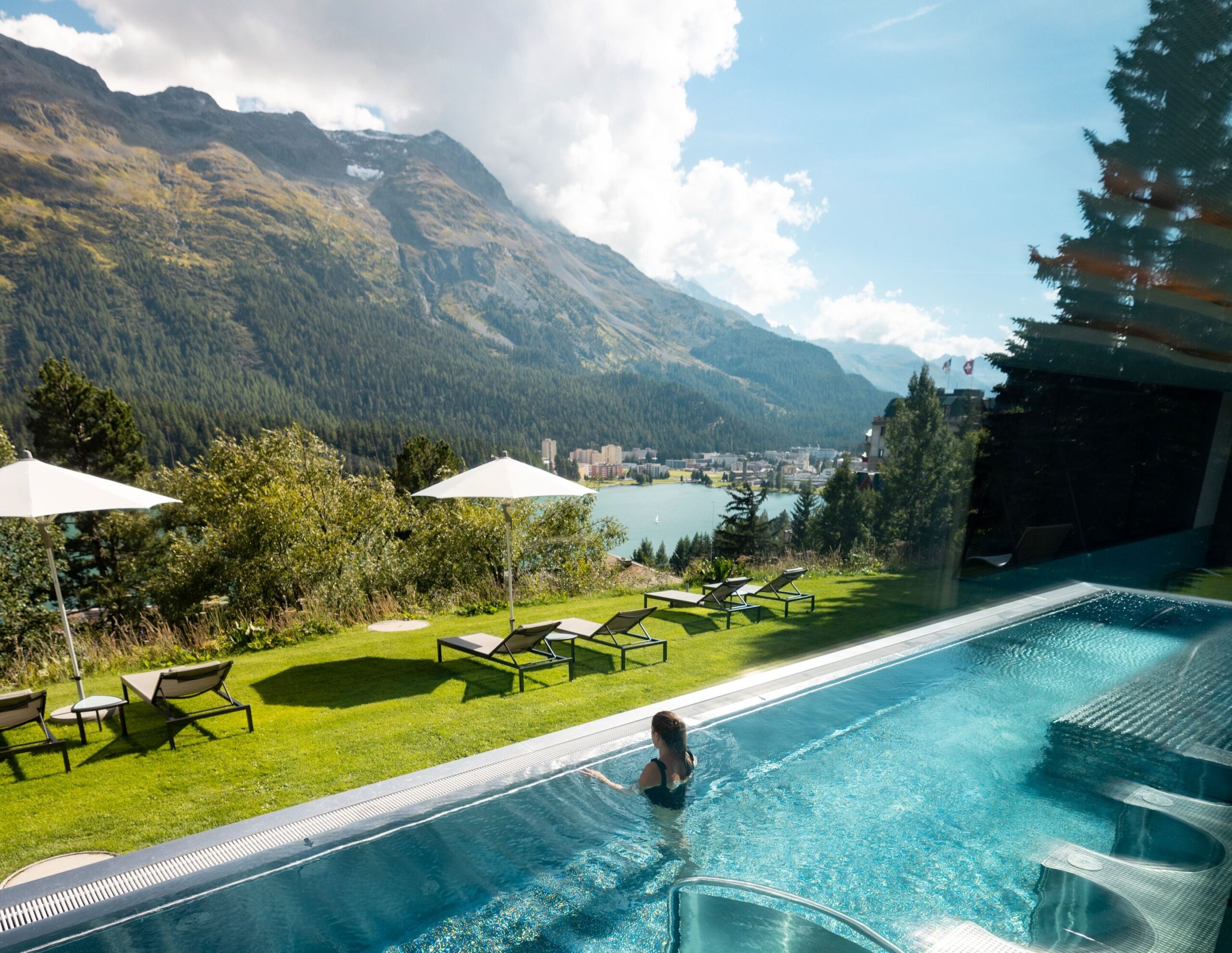 Woman in pool at Kulm Hotel St. Moritz, overlooking lake and mountains in Switzerland.