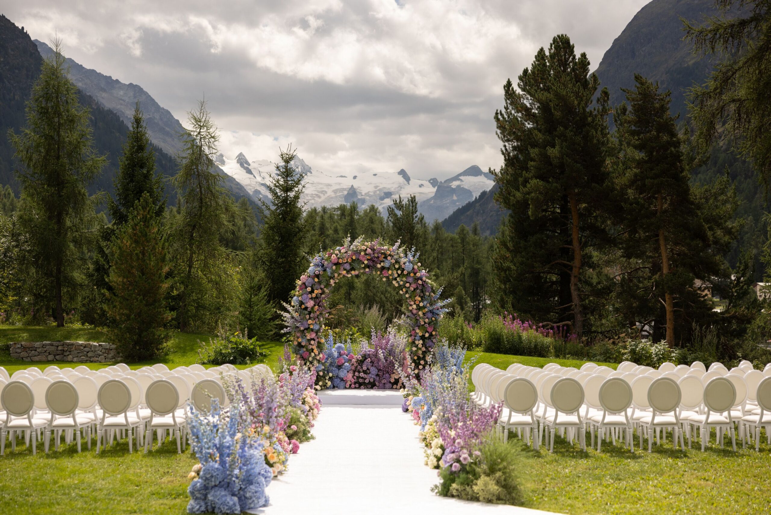 Swiss Alps wedding at Grand Hotel Kronenhof. Outdoor ceremony with floral arch and mountain views.