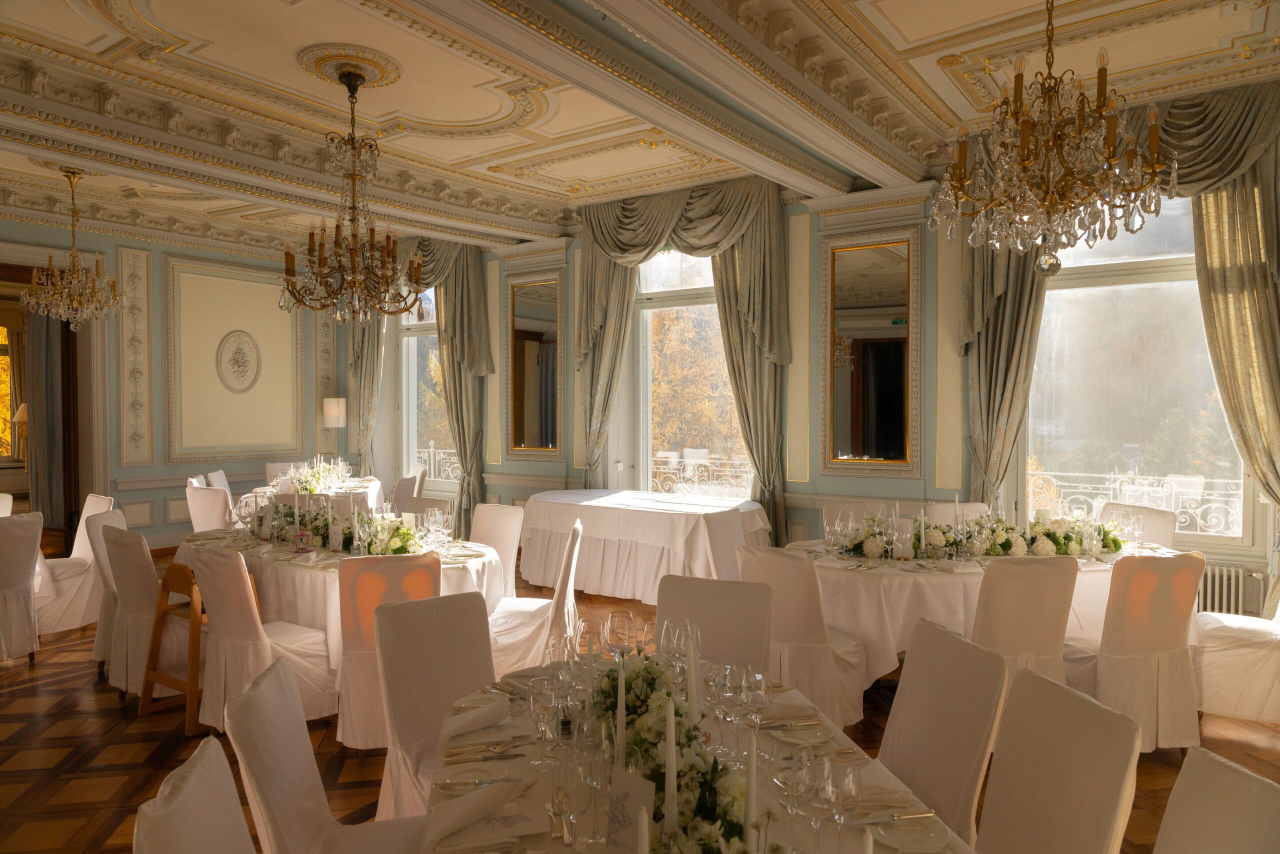 Swiss Alps wedding reception at Grand Hotel Kronenhof with elegant table settings and chandeliers.