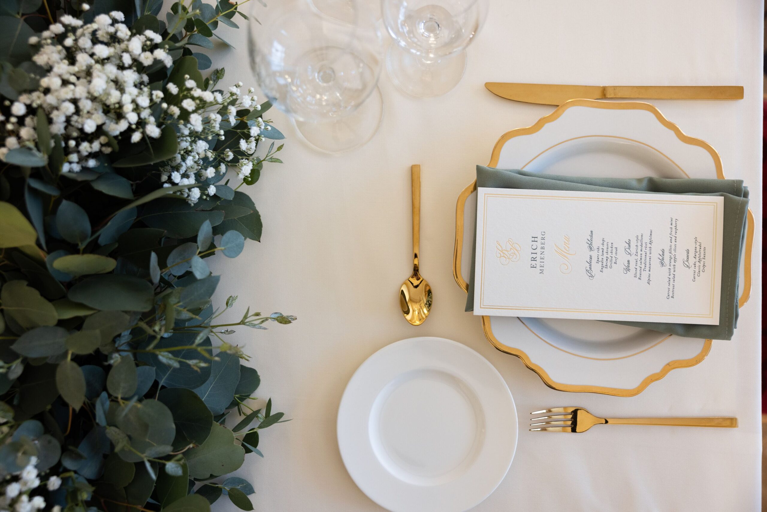 Elegant Swiss Alps wedding table setting with gold cutlery and menu. Grand Hotel Kronenhof detail.