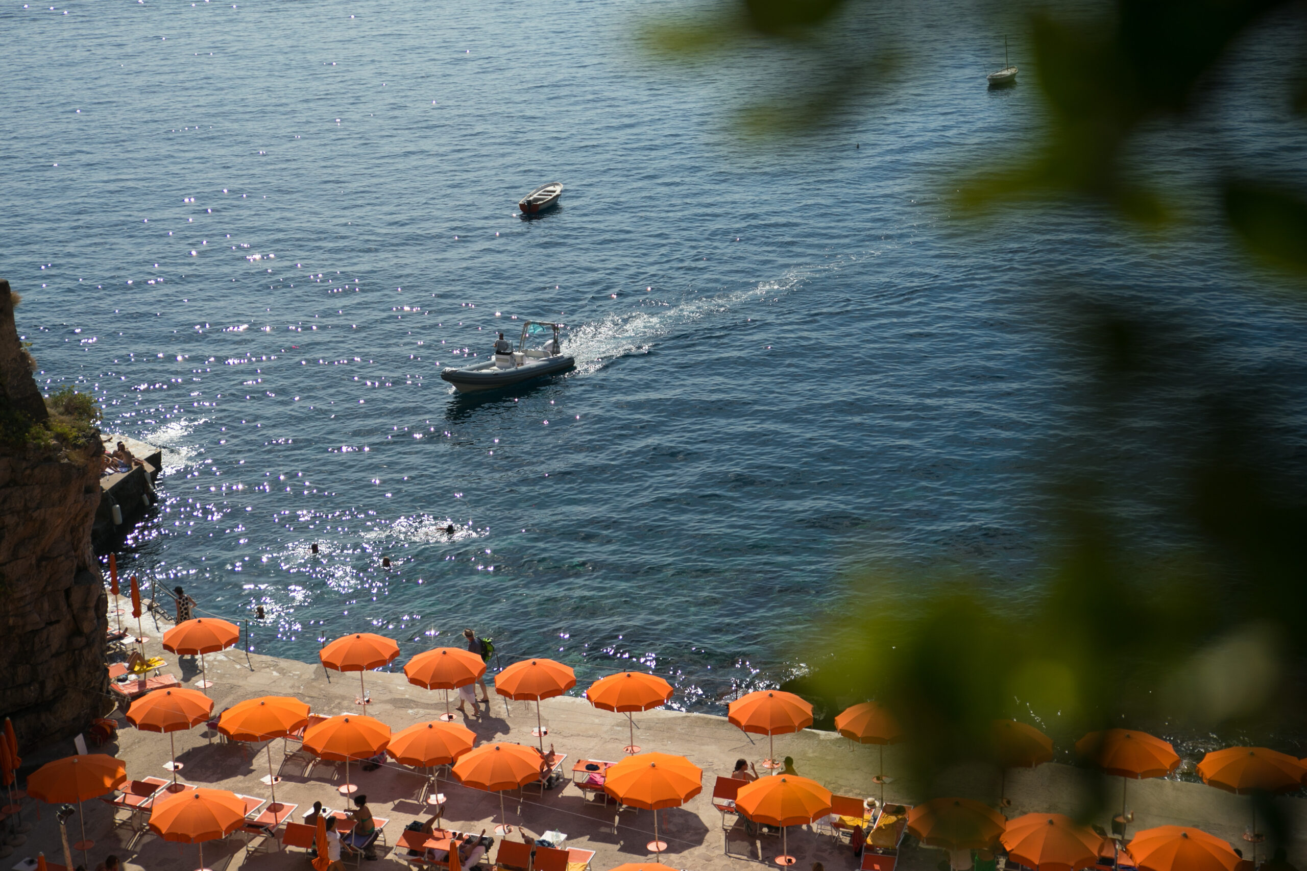 Orange umbrellas line the beach near Casa Angelina, Amalfi Coast. Boat in the sea.
