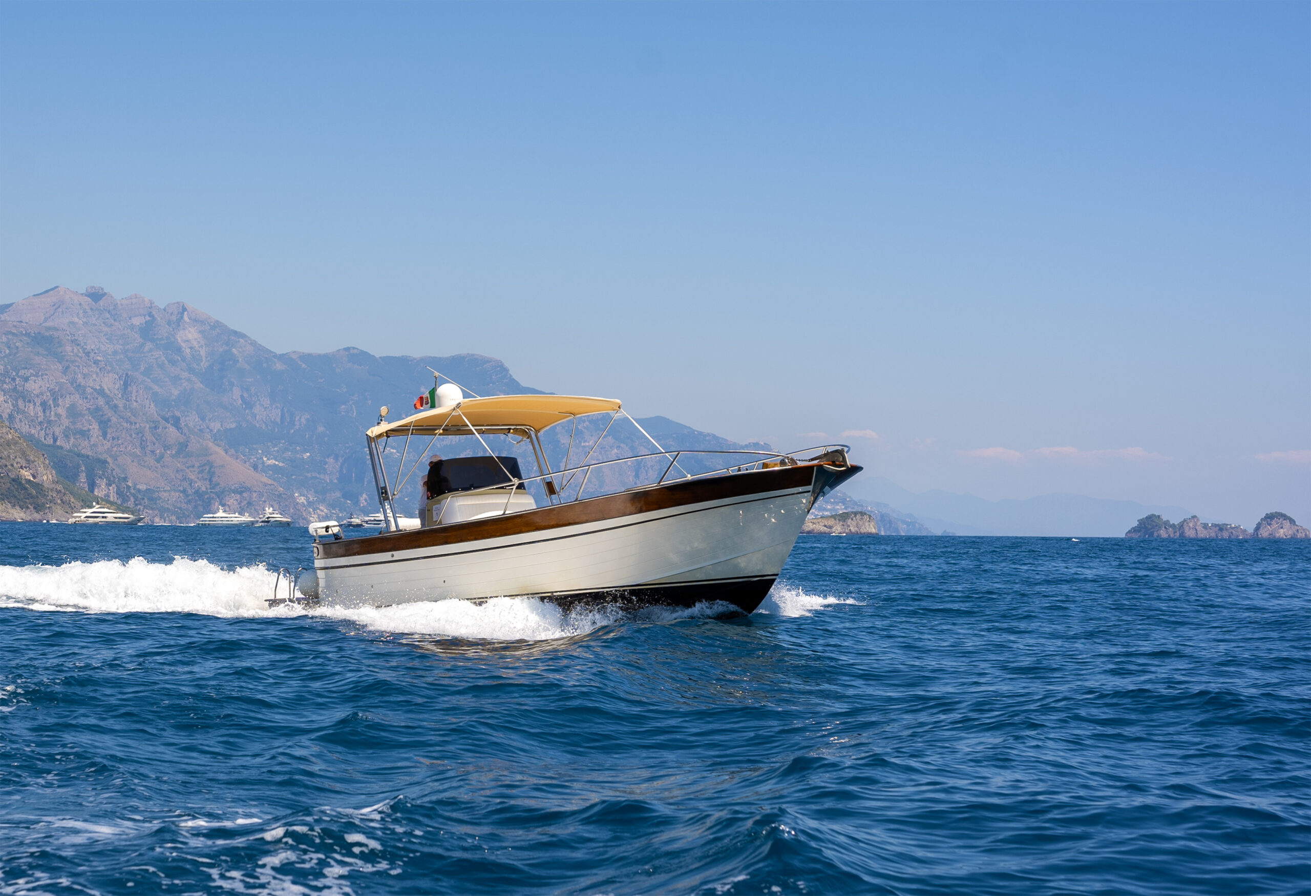 Boat cruising on the Amalfi Coast with mountains in the background, ideal for a Casa Angelina wedding.