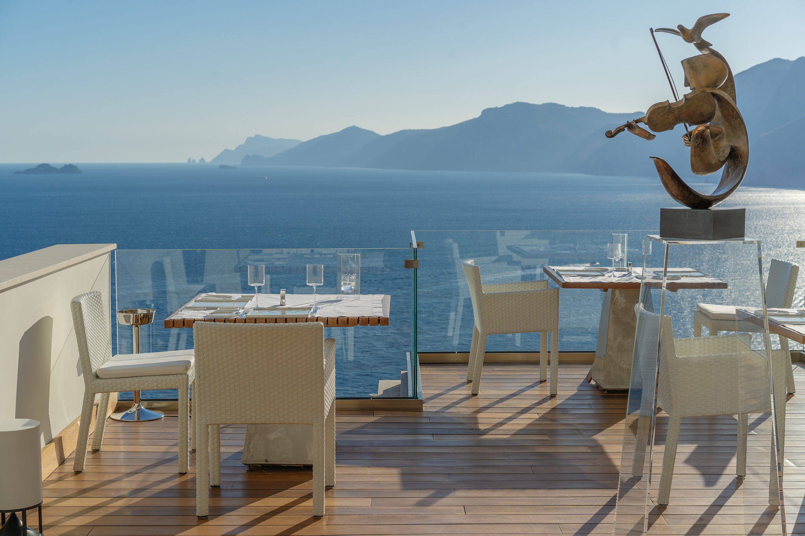 Outdoor dining at Casa Angelina on the Amalfi Coast with ocean view and sculpture.