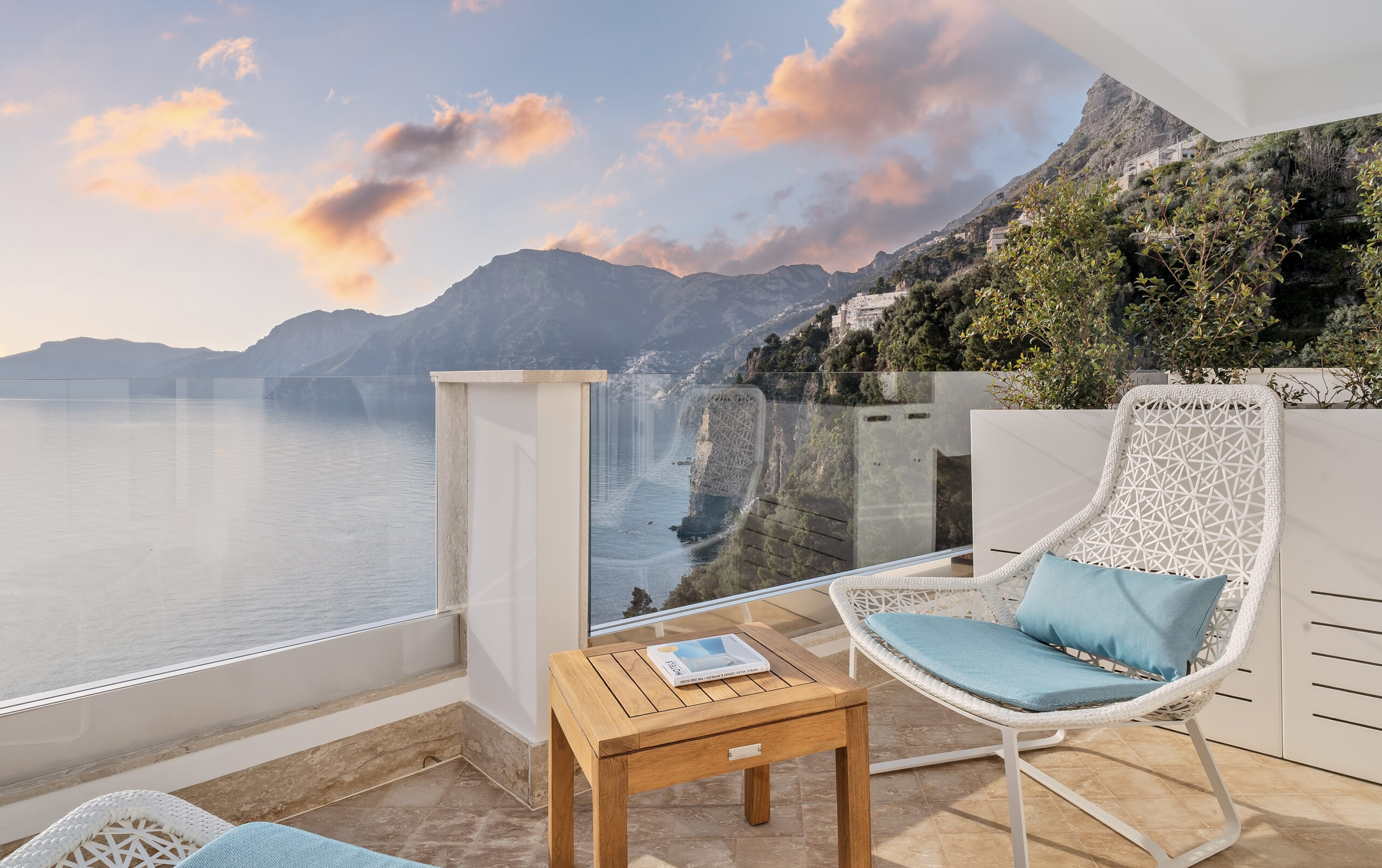 Casa Angelina balcony view of Amalfi Coast mountains and ocean at sunset.