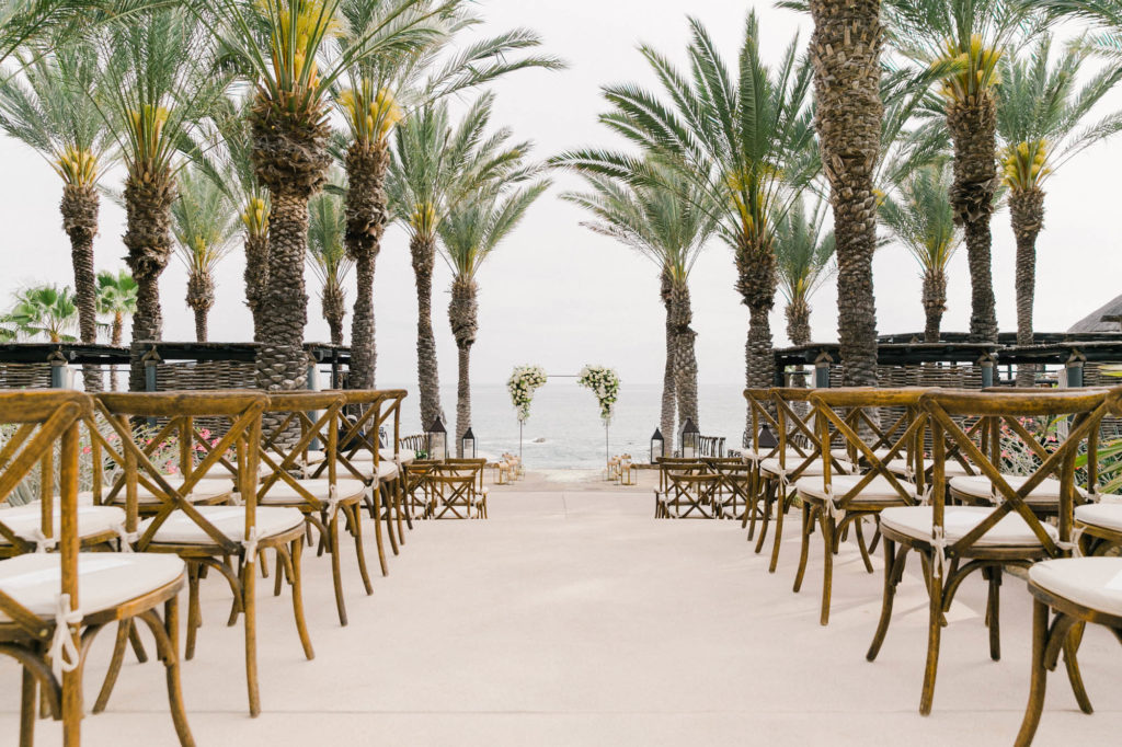 Long wedding aisle outdoors facing the beach with palm trees