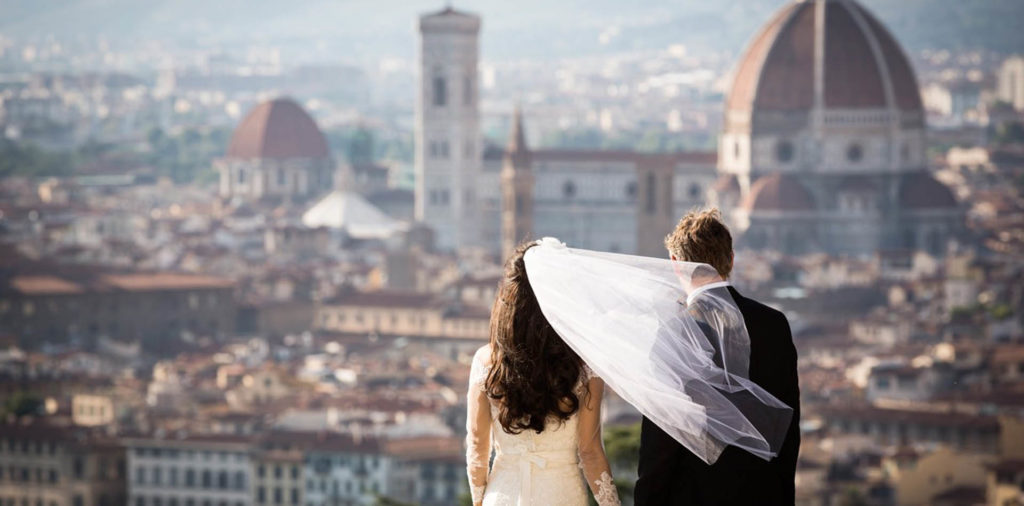 Wedding couple with veil in the wind overlooking Florence Italy