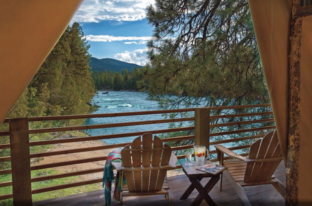 2 empty adirondak chairs facing a raging river from a luxury hotel balcony