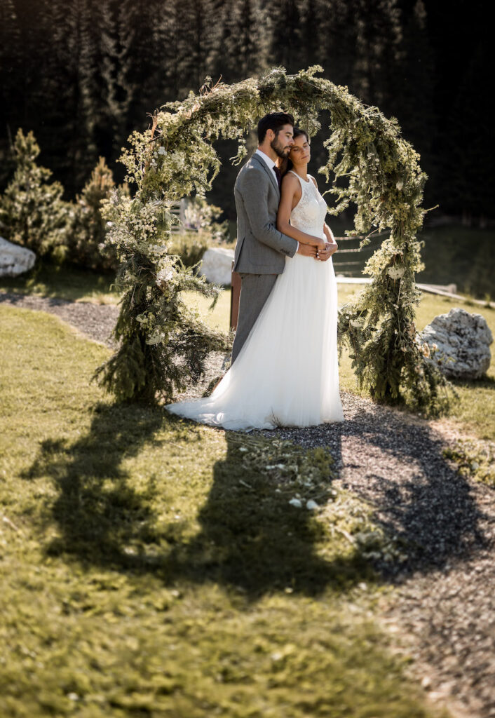 wedding couple in greenery circled arch