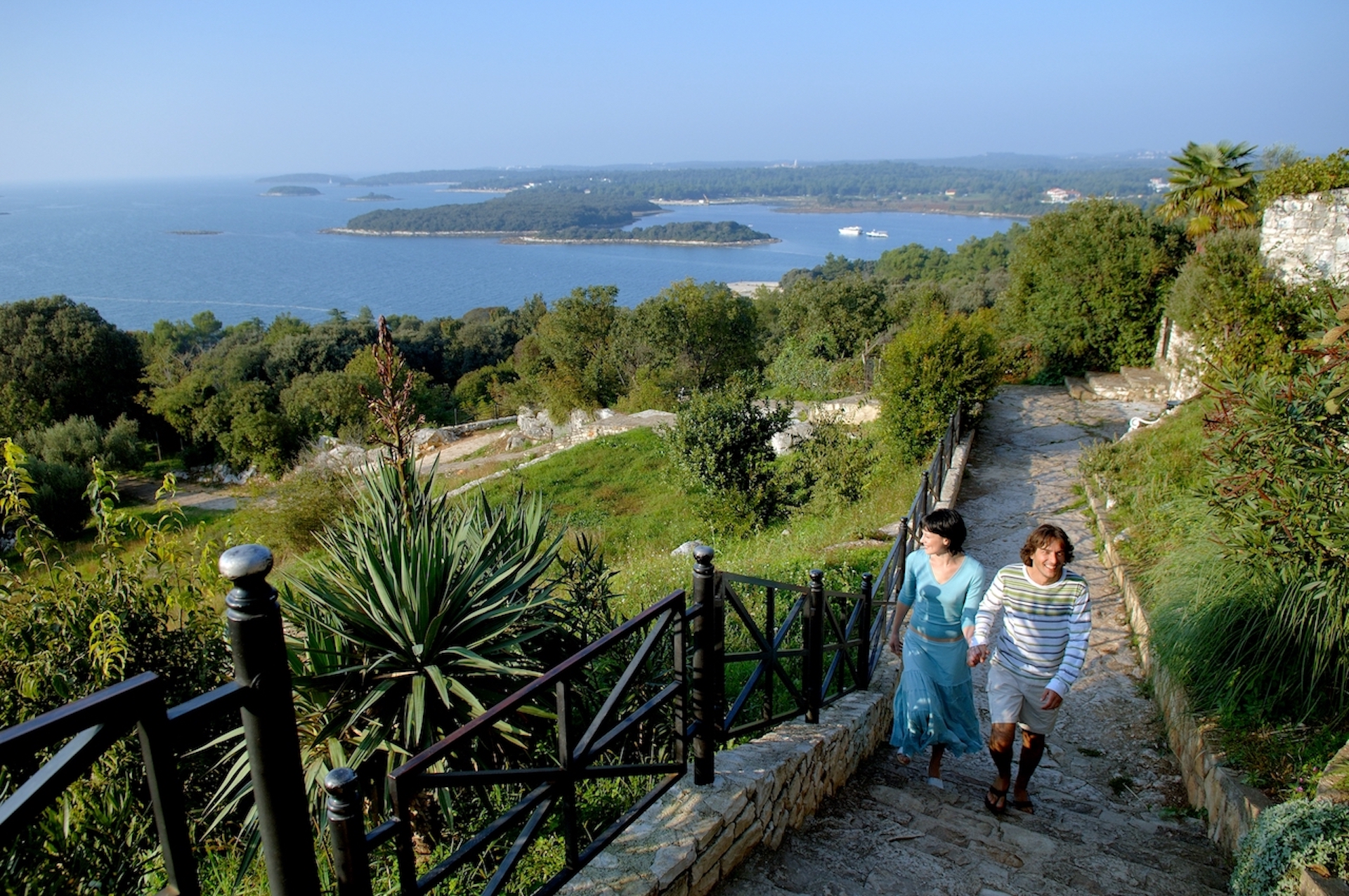 couple climbing a cobblestone path overlooking the landscape and sea