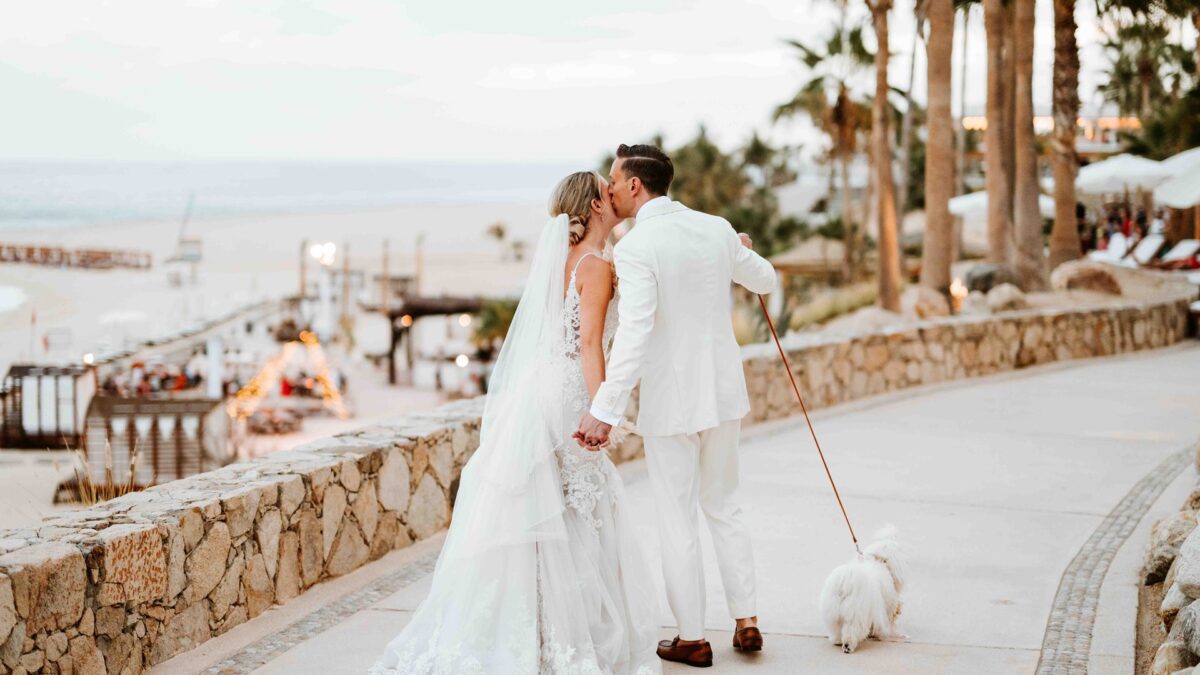 Los Cabos destination wedding: Bride and groom kissing, with dog.